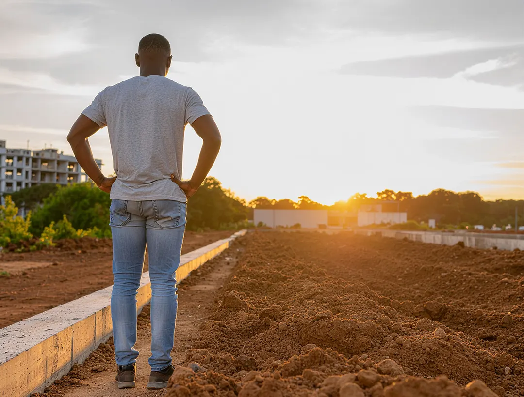 A man standing at a building site at sunset