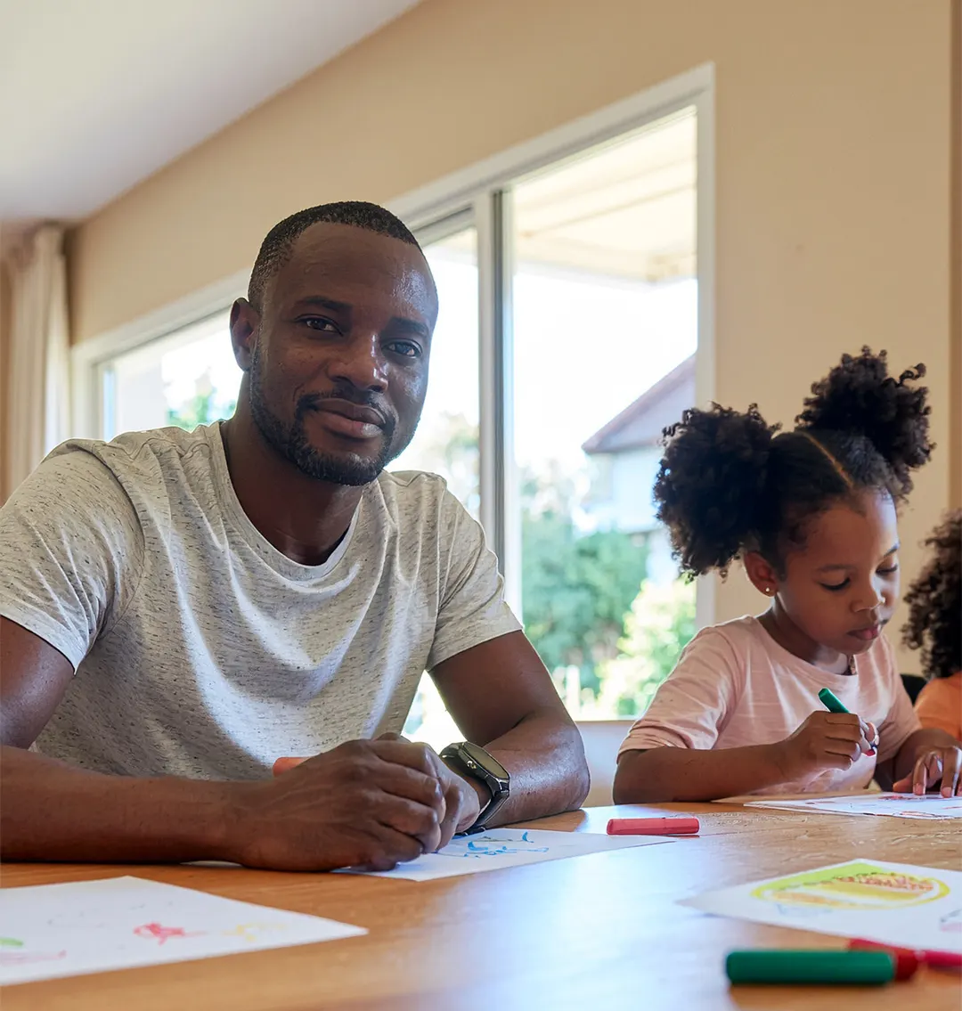 A father and daughter drawing at a table near a window